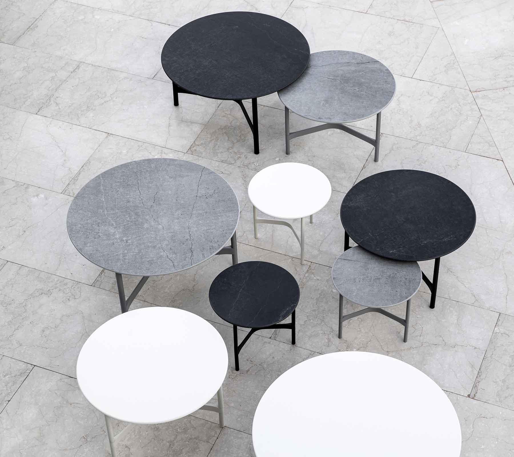 Een collectie van verschillende ronde tafels in verschillende maten en kleuren, waaronder zwart, grijs en wit, esthetisch gerangschikt.