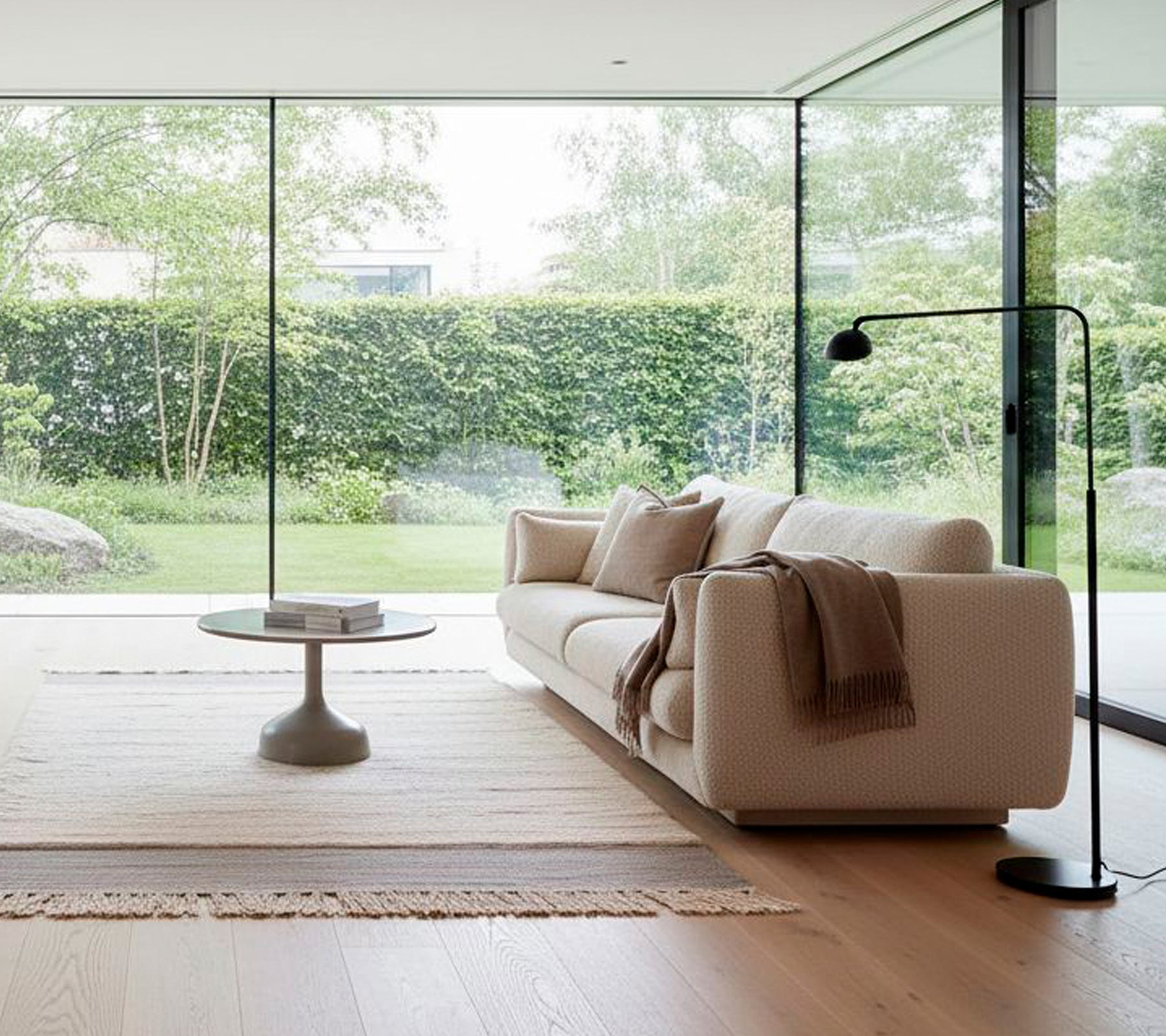 Moderne witte bank met een zwarte vloerlamp en een ronde salontafel in een minimalistische woonkamer.