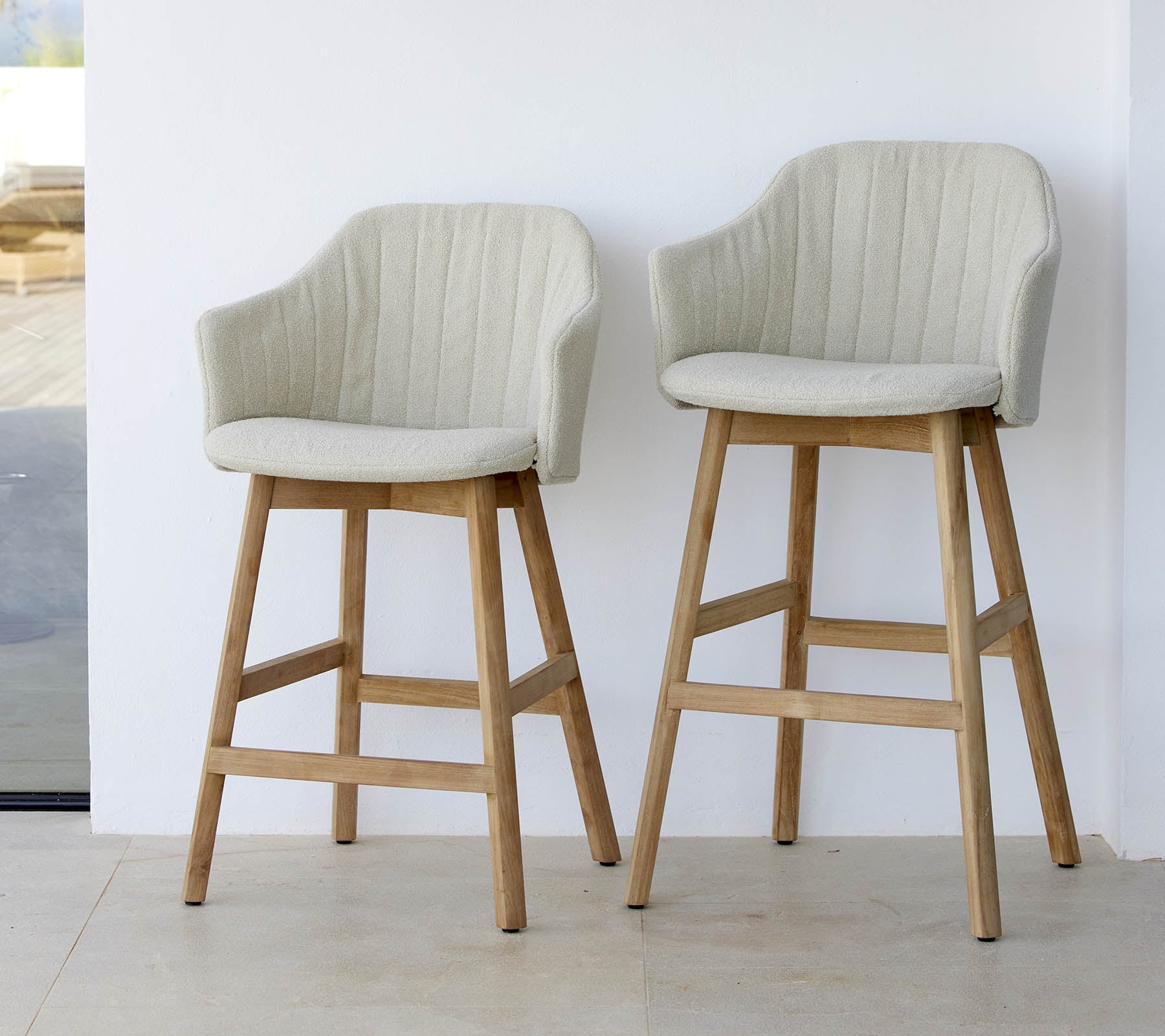Twee stijlvolle, lichtgekleurde stoelen met gebogen rugleuning en houten poten, die een modern en comfortabel ontwerp laten zien.