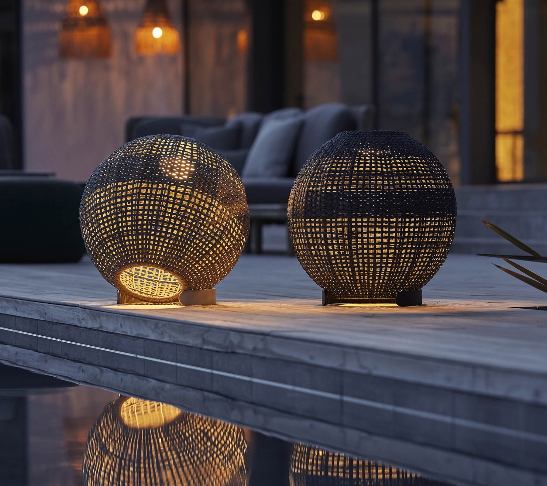 Twee ronde illusielampen met ingewikkelde patronen, die warm licht en reflecties op een oppervlak werpen, waardoor een gezellige sfeer ontstaat.