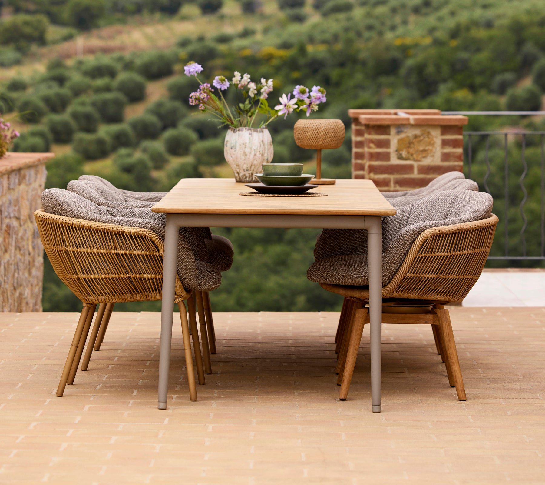 Stijlvolle eetopstelling met een houten tafel, twee Stay-stoelen met aluminium poten, en een vaas met bloemen en decoratieve accessoires.