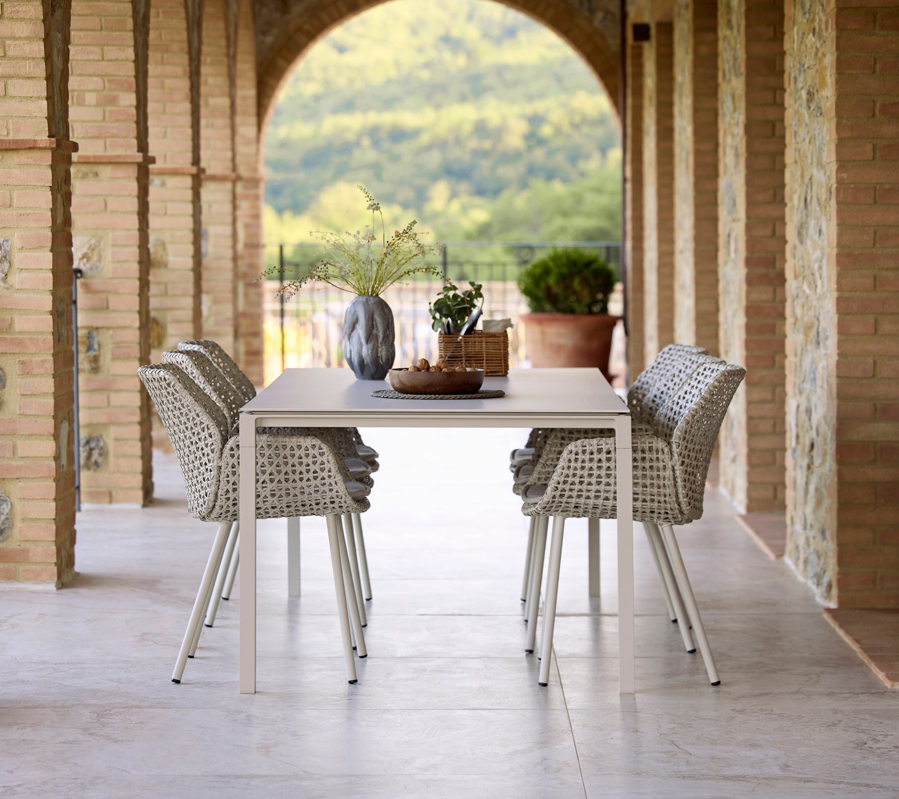 Elegante eetopstelling met een Pure zand eettafel omringd door Vibe eetstoelen, geaccentueerd met een vaas en decoratieve elementen.