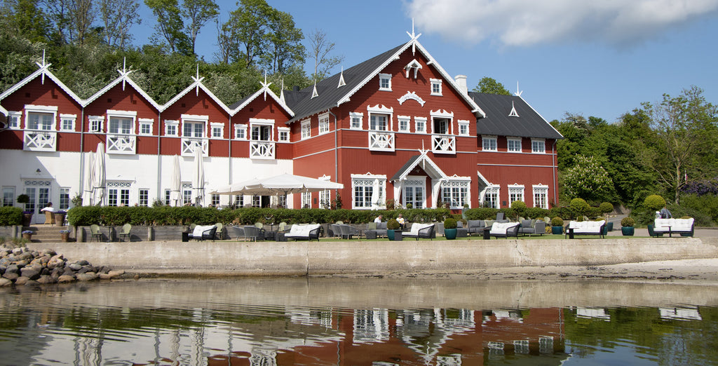 Red hotel building with white exterior details, Danish Dyvig Badhotel, outdoor lounge with sea view