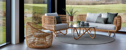 Comfortabele loungezitplaatsen met rattan meubels, zachte kussens, een glazen tafel en decoratieve planten, die een stijlvolle en uitnodigende sfeer creëren.