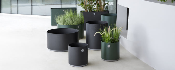 Moderne zwarte en groene plantenbakken met groenarrangement in een hedendaagse setting.
