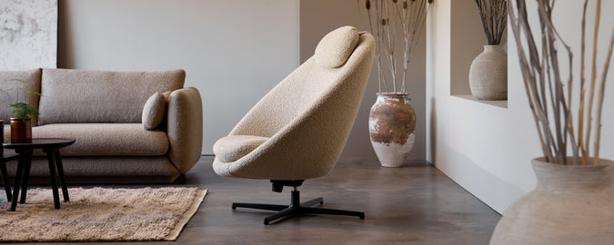 Beige draaistoel en grijze bank in een moderne lounge-instelling.