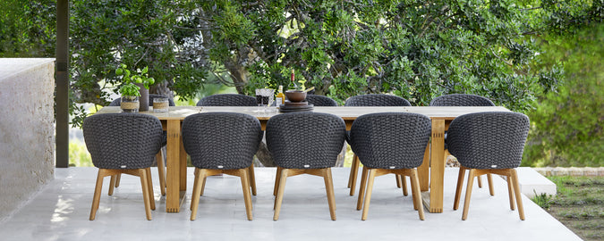 Moderne buitenset met zwarte stoelen en een houten tafel.