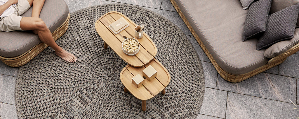Moderne lounge-instelling met een bruine salontafel, een grijze bank en beige kussens.