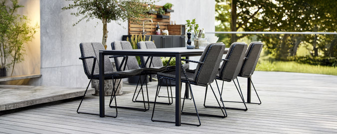Zwarte eettafel met grijze stoelen in een moderne buitenomgeving.