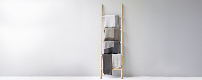 Moderne handdoekladder met beige, grijze en witte handdoeken.