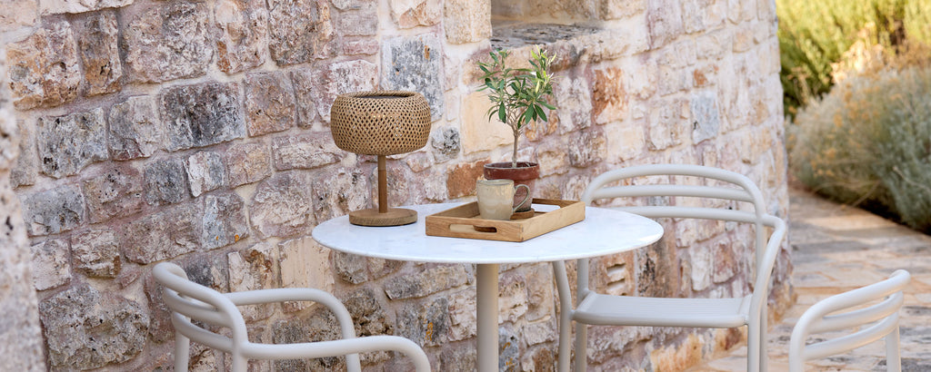 Moderne buitenomgeving met een witte tafel, witte stoelen en bruine decoratieve elementen.