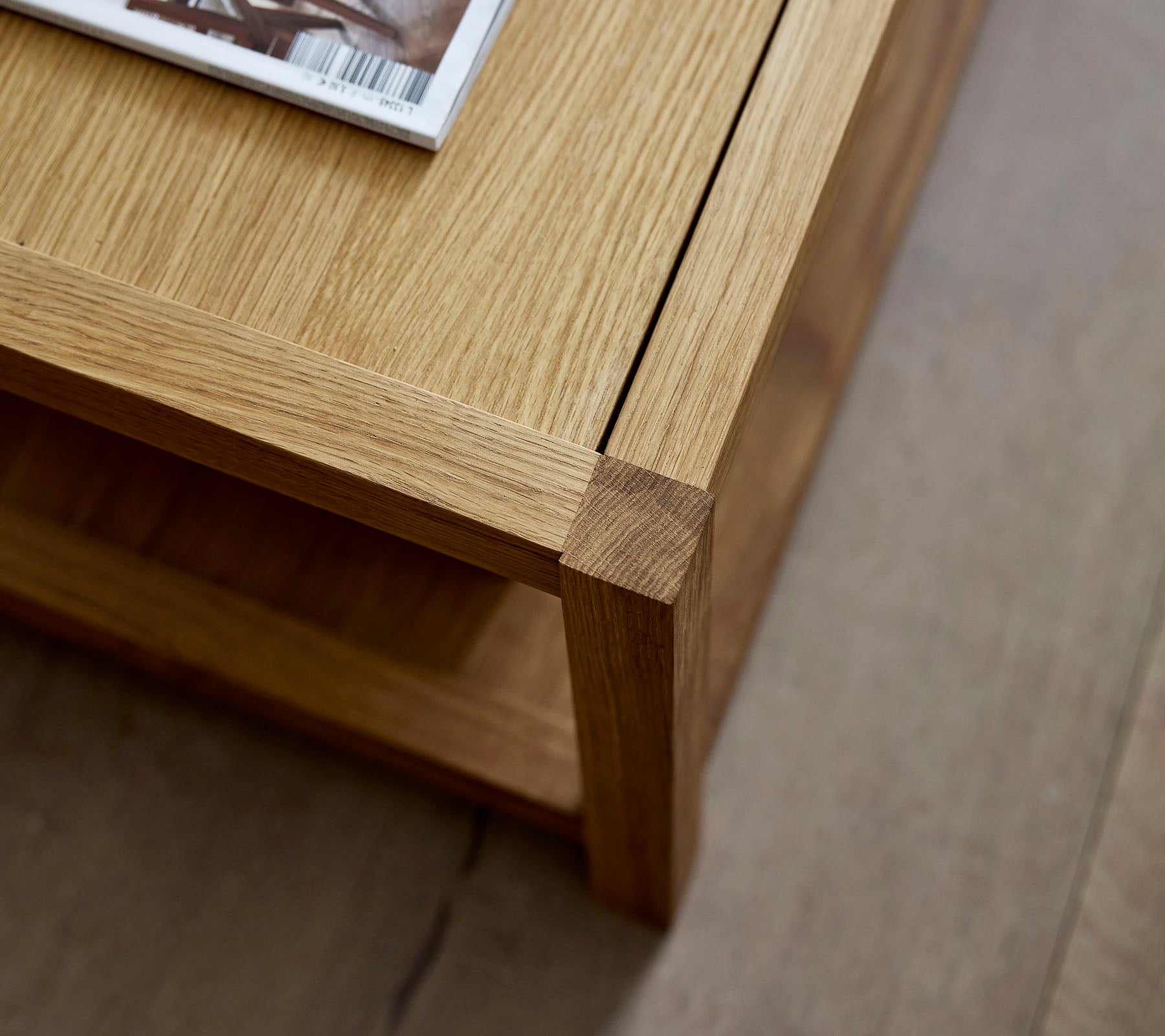 Houten salontafel met een schoon ontwerp, met een tijdschrift bovenop en een minimalistische onderste plank voor extra opslag.