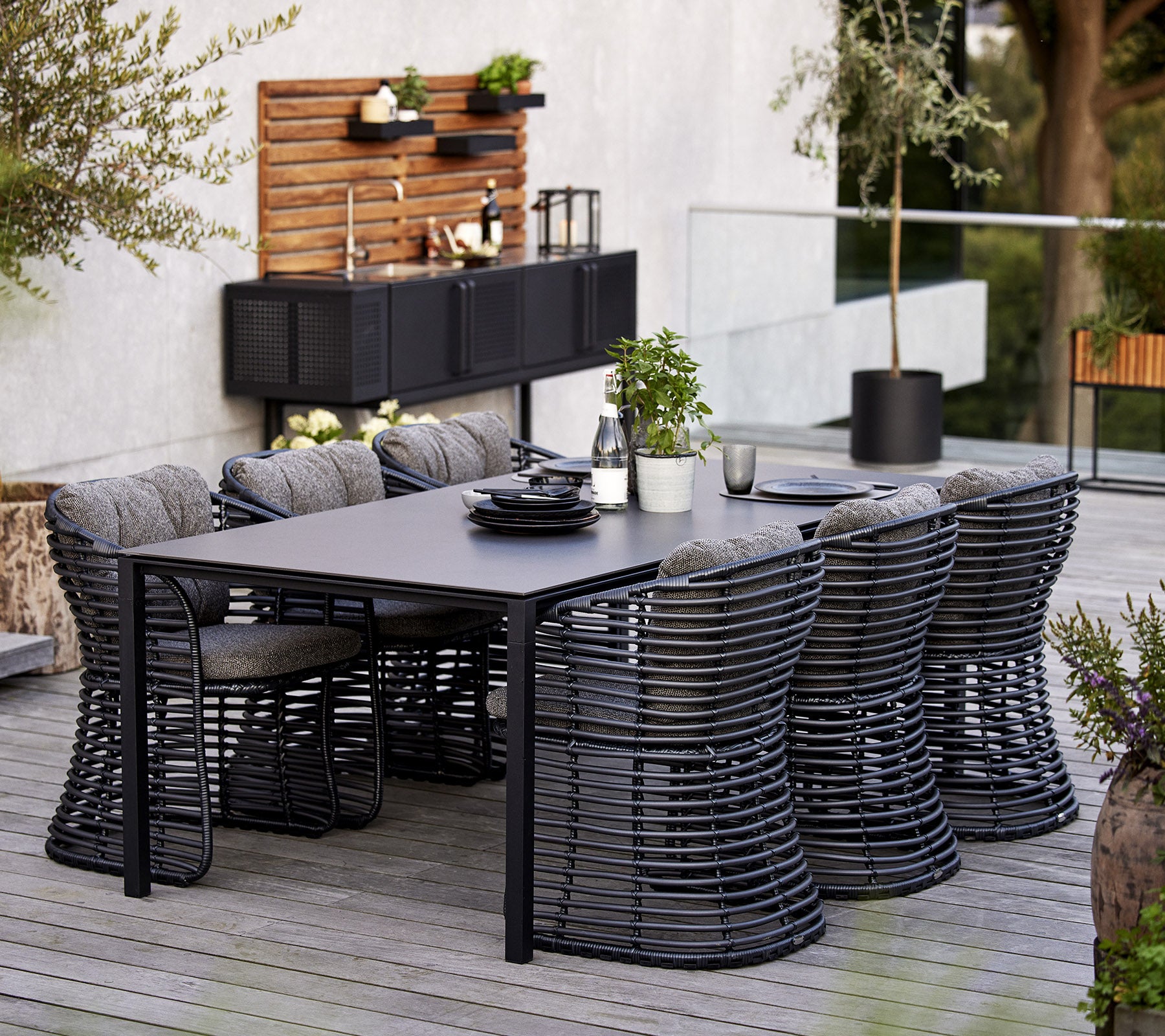 Een modern eethoek met een rechthoekige tafel en zes stijlvolle mandstoelen, aangevuld met decoratieve elementen op de achtergrond.
