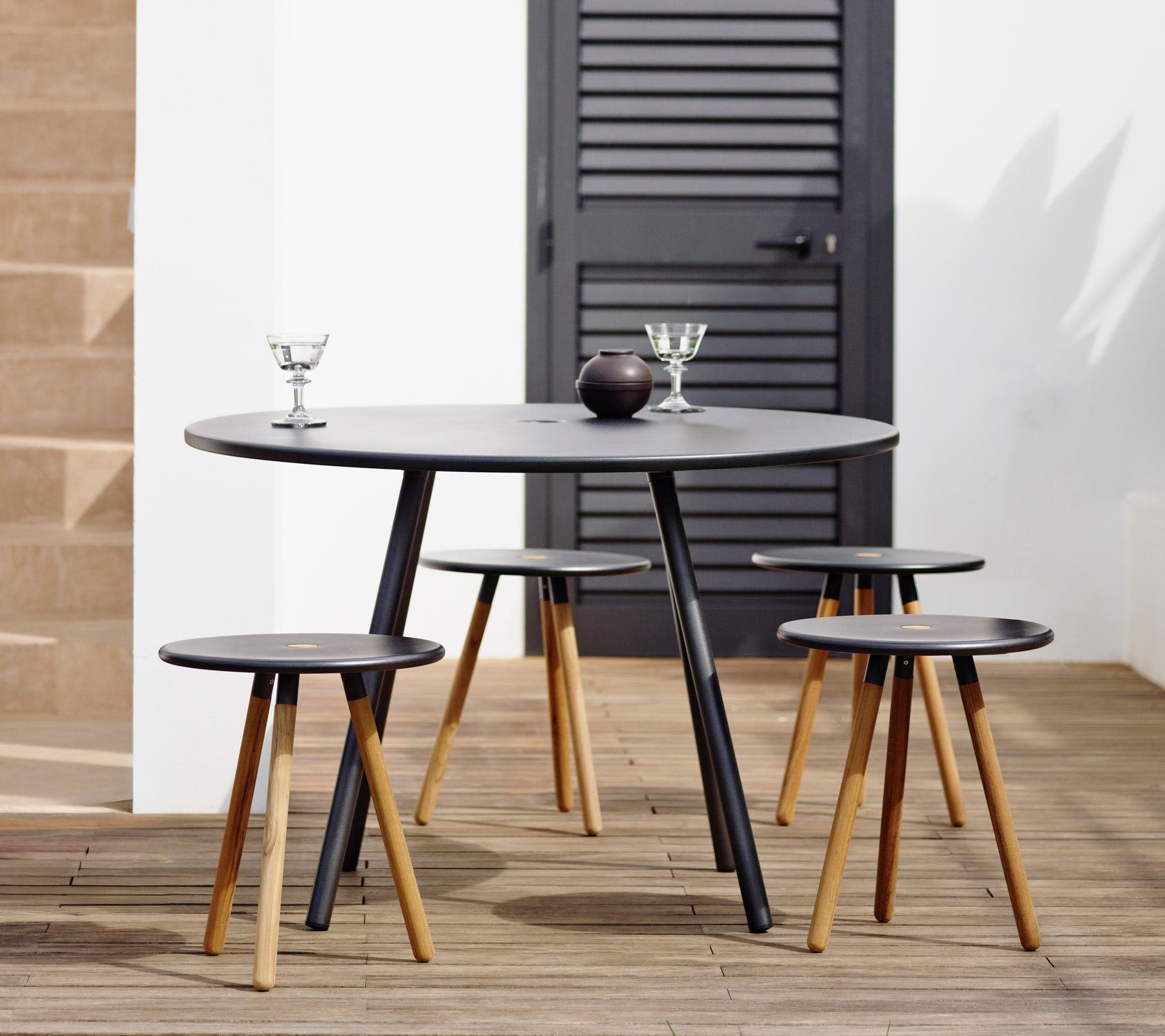 Modern zwart tafeltje met bijpassende barkrukken in een stijlvolle loungeomgeving.