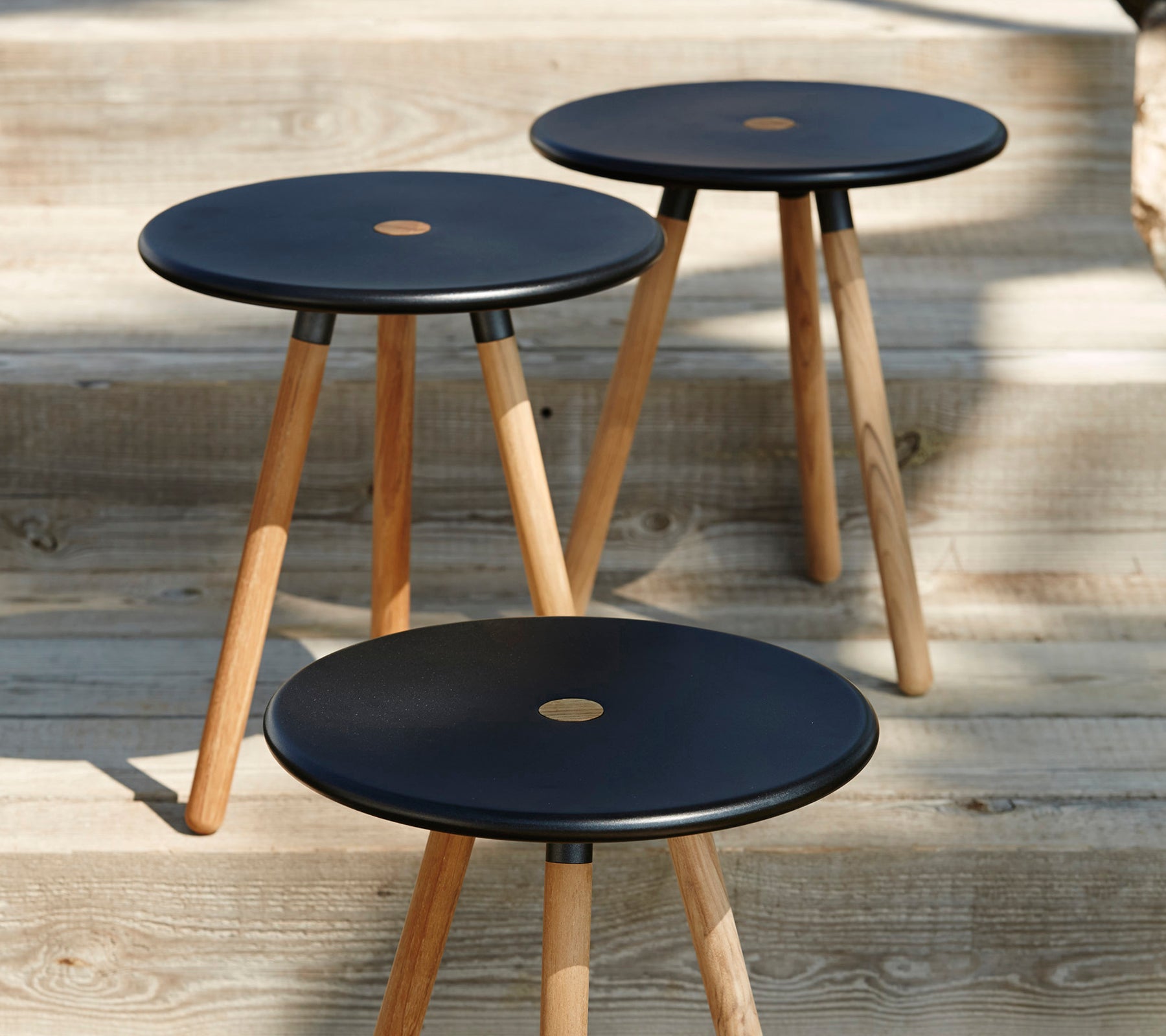Drie moderne zwarte barkrukken met houten poten op een houten oppervlak.