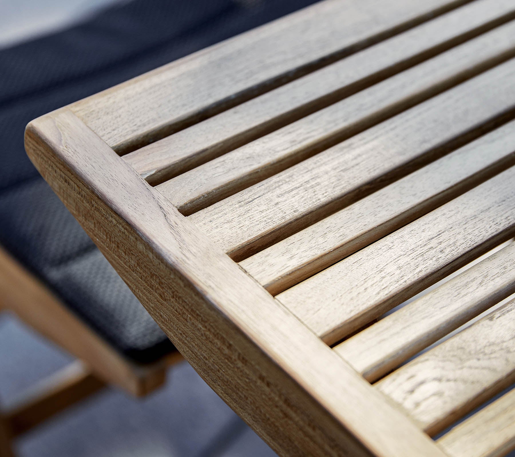 Close-up van een houten tafelrand met lattenontwerp, dat de natuurlijke nerf en textuur van het hout toont.