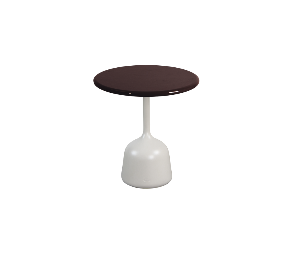 Burgundy ronde tafel met een witte basis in een moderne lounge-setting.