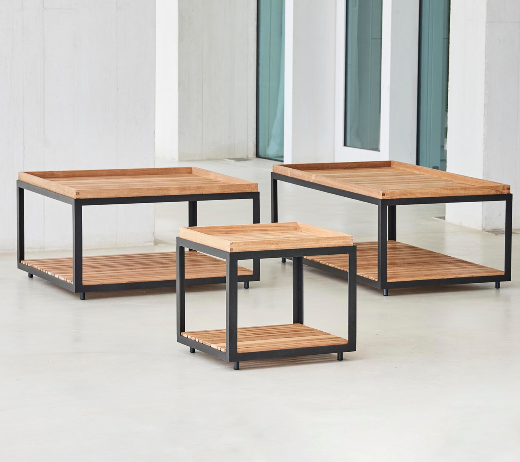 Drie stijlvolle houten salontafels met zwarte metalen frames in verschillende maten, met open onderplanken voor opslag en presentatie.