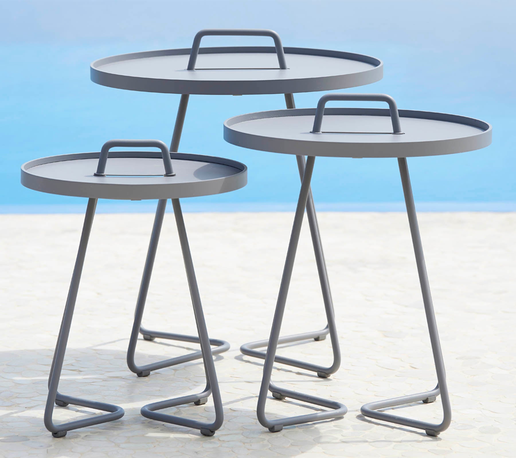 Drie moderne ronde tafels met slanke metalen frames en vlakke oppervlakken, gerangschikt in verschillende maten. Perfect voor veelzijdige stylingmogelijkheden.