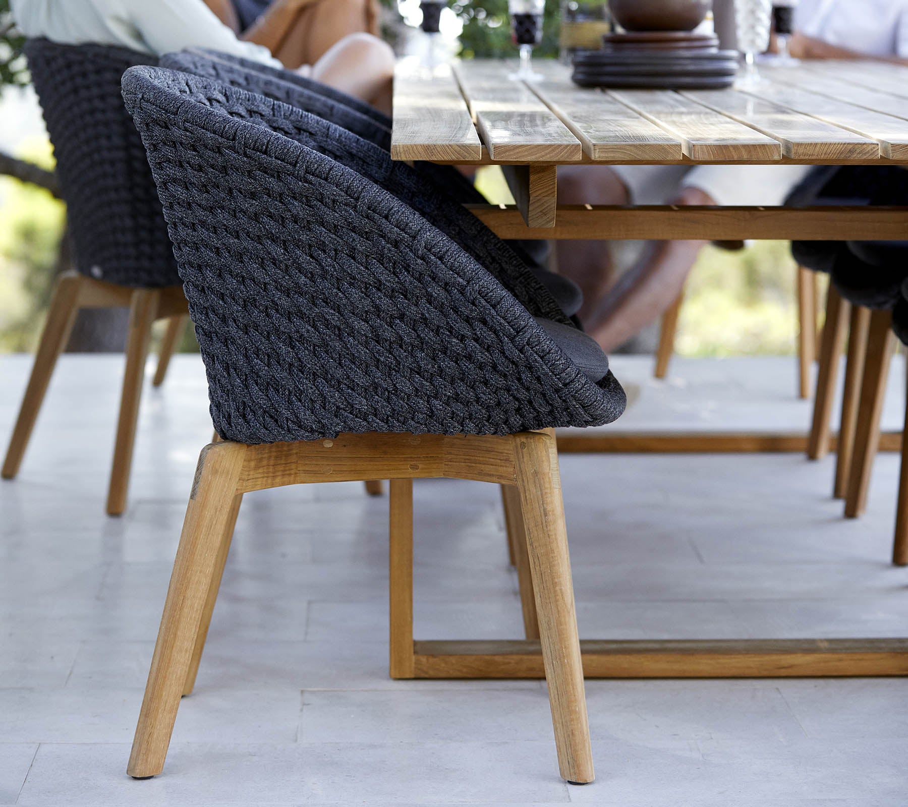 Stijlvolle geweven stoel met een houten basis, gepositioneerd naast een tafel, die een modern ontwerp toont, perfect voor verzamelruimtes.