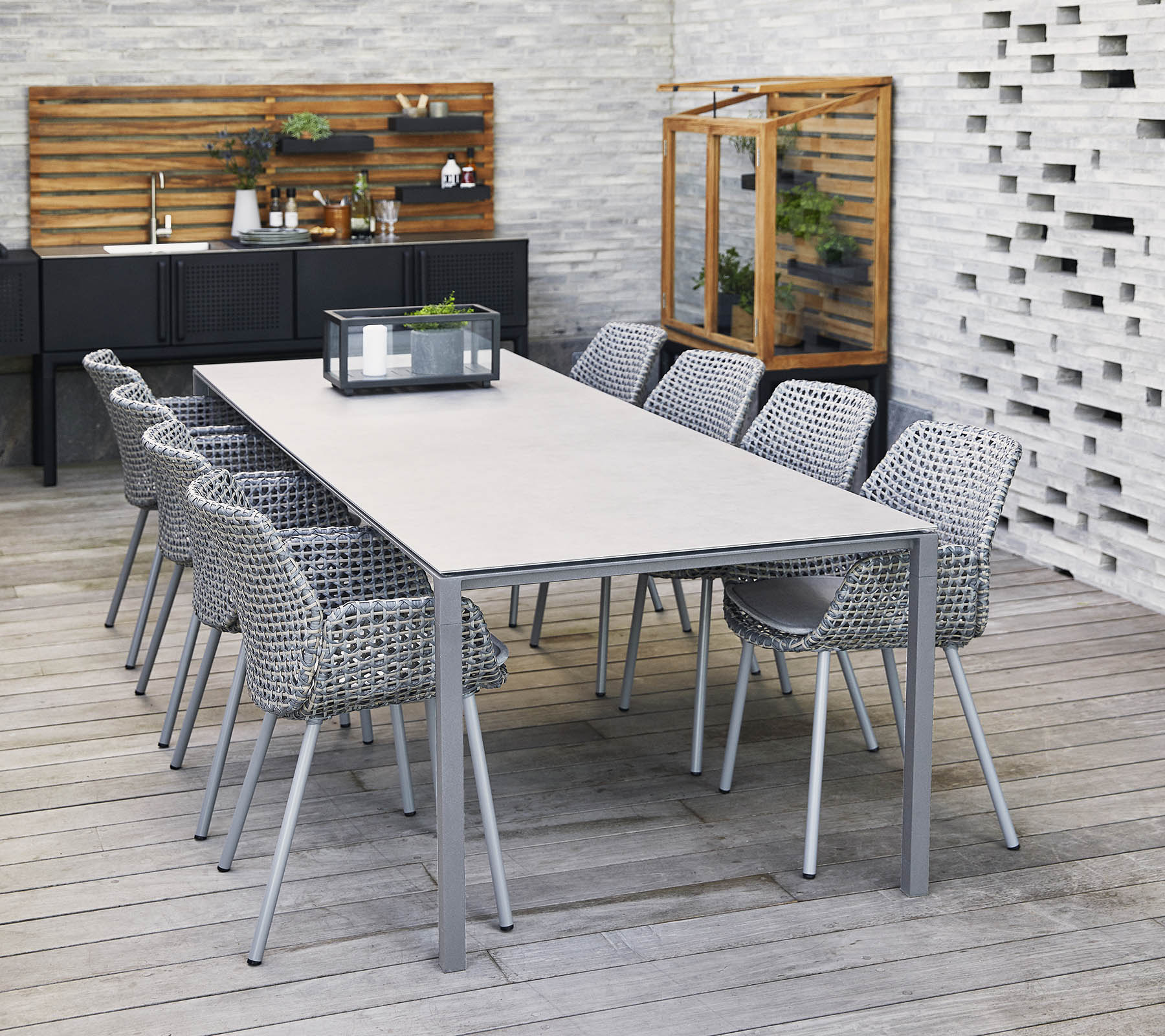 Een stijlvol lange tafel omringd door gevlochten stoelen, met een middenstuk en decoratieve elementen in een moderne setting.