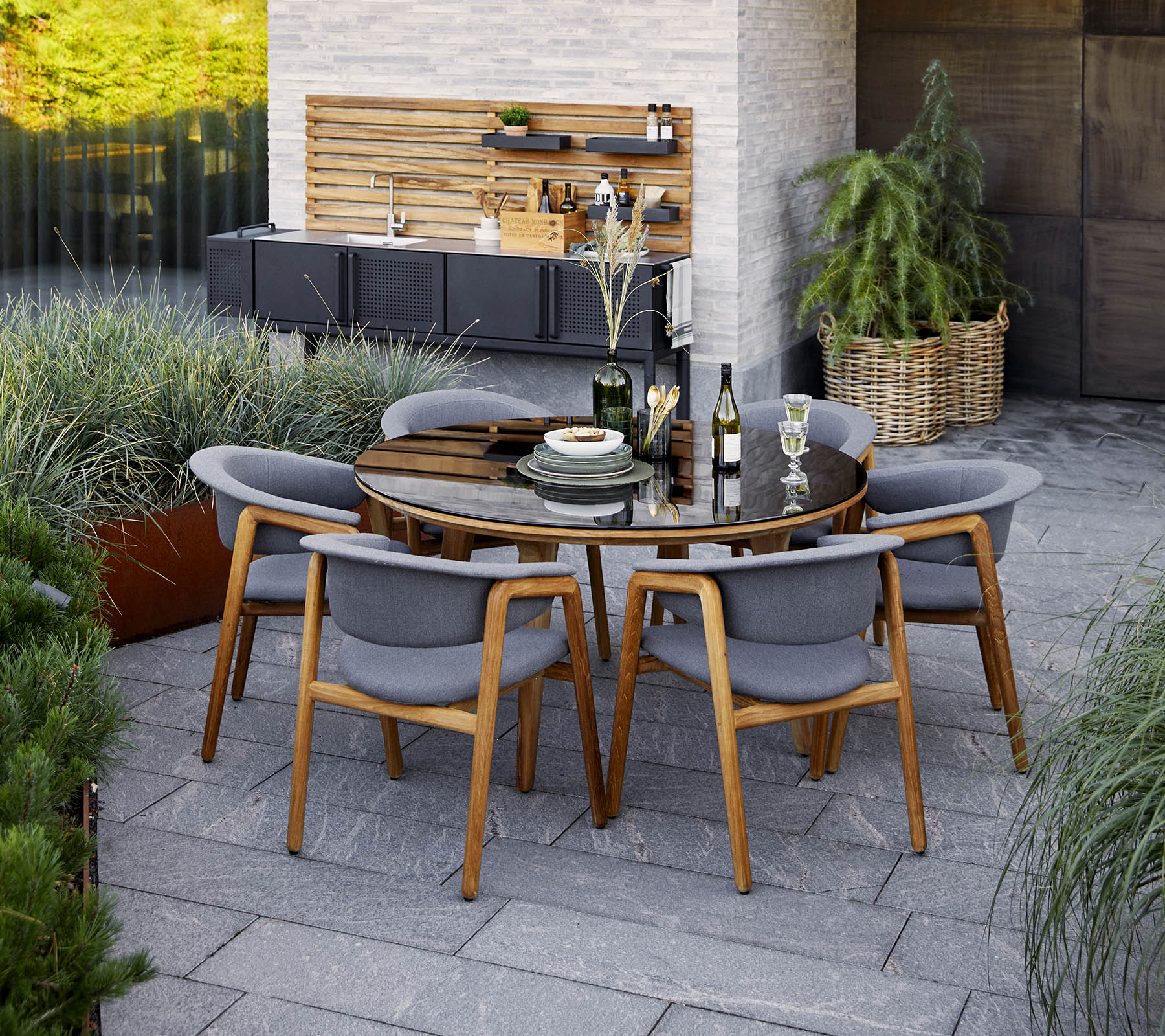 Een moderne ronde eettafelset met grijze stoelen, met decoratieve elementen en groen in de achtergrond.