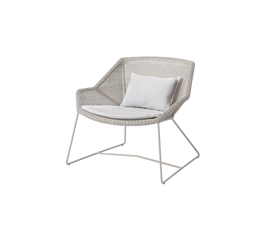 Moderne witte stoel met een witte kussen in een lounge setting.