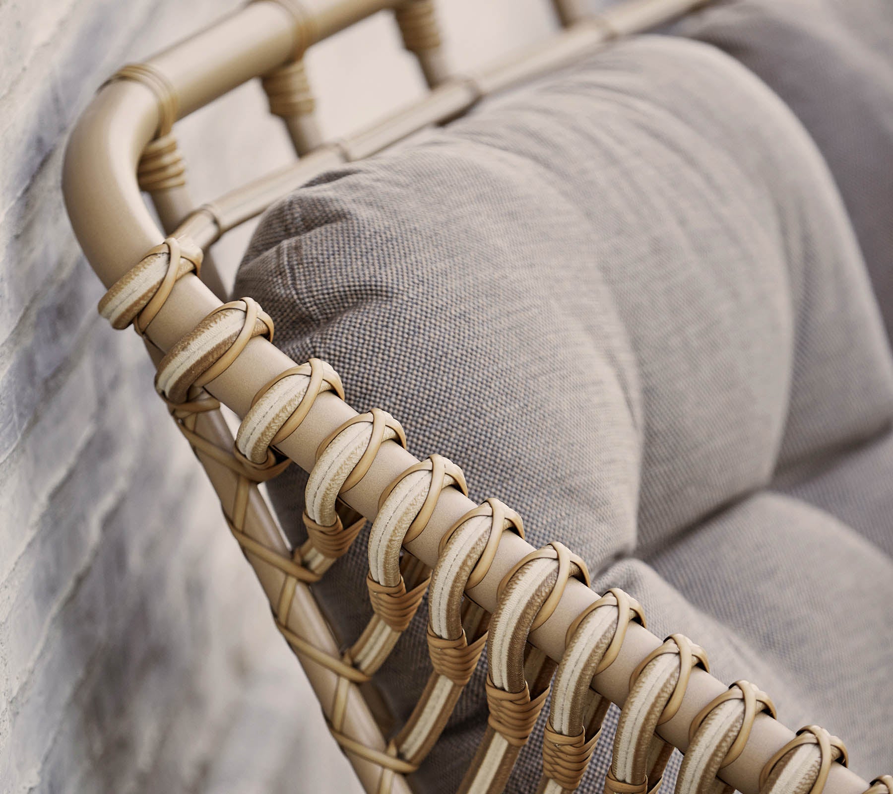 Stijlvolle zitoplossing met een beige geweven frame en zachte grijze kussens, perfect om moderne decor te verbeteren.