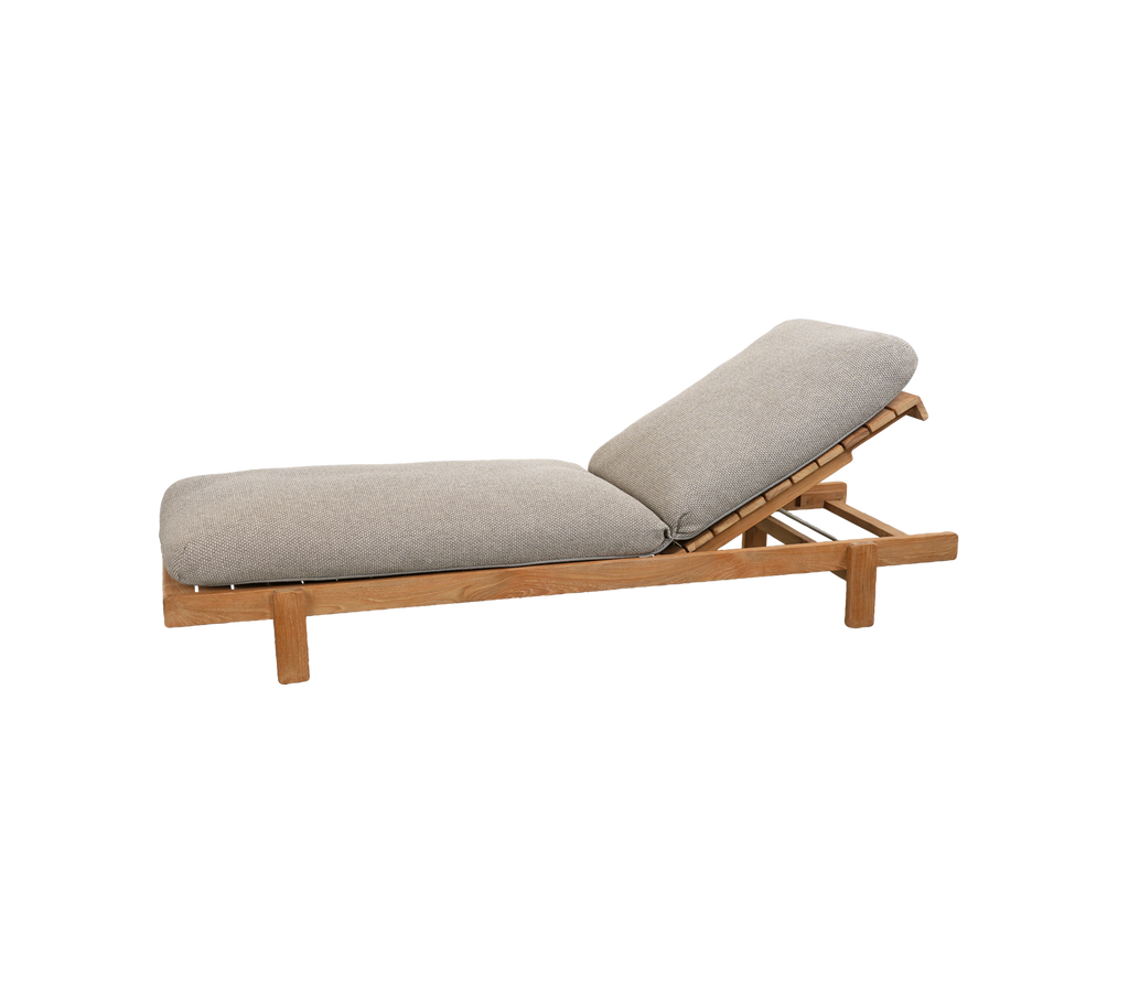 Lichtbruine lounge stoel met een grijs kussen en een verstelbare rugleuning.