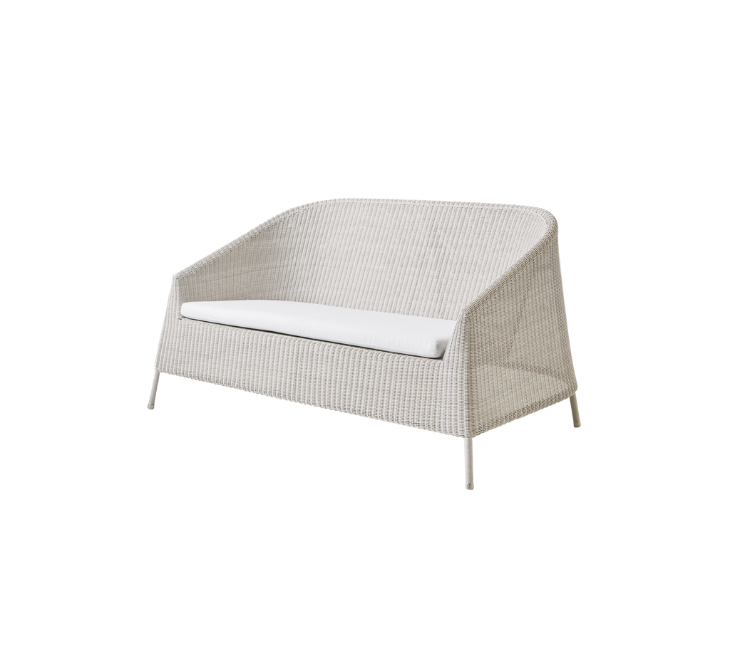 Moderne zandkleurige loveseat met een wit kussen in een minimalistisch design.