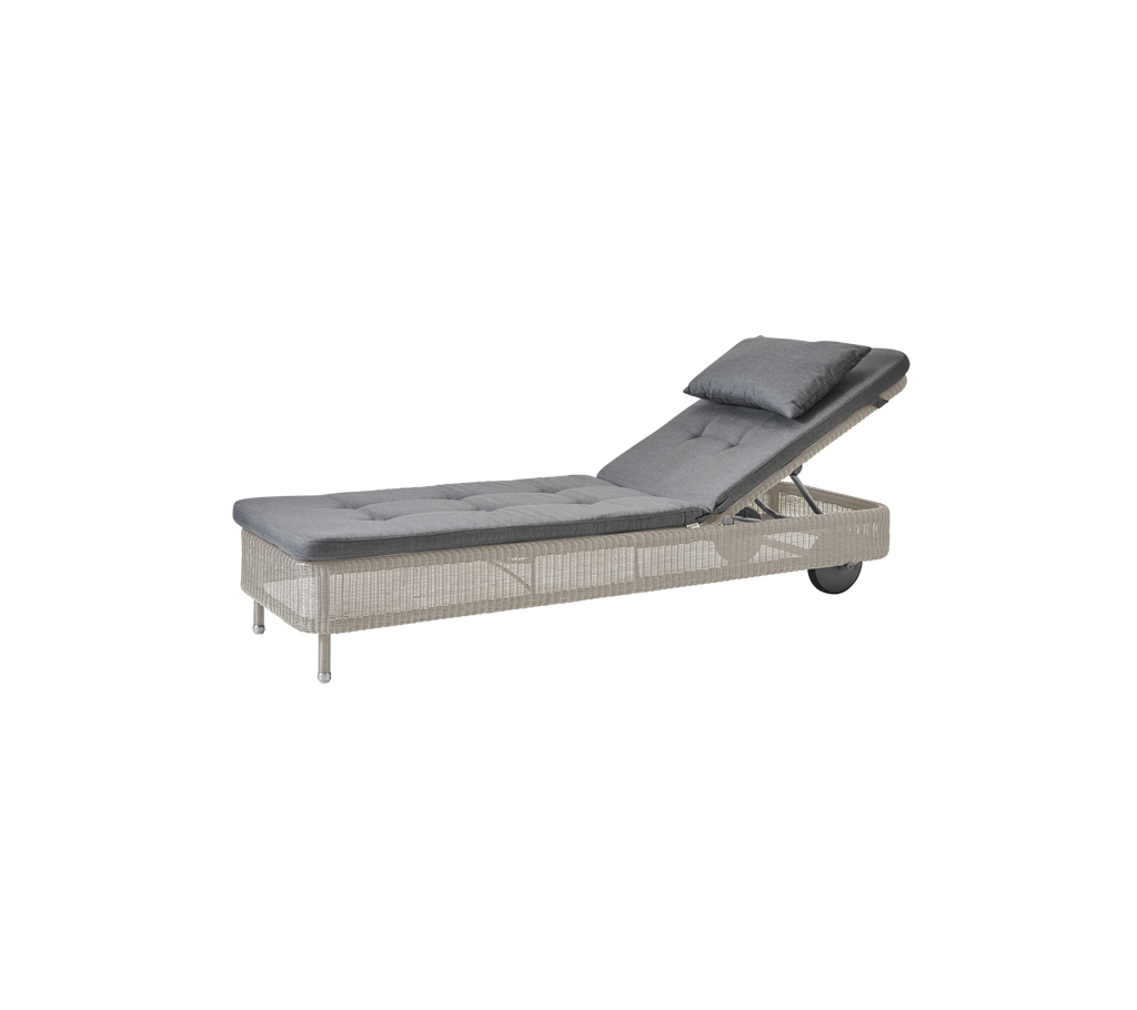 Moderne grijze chaise longue met een zandkleurig kussen.