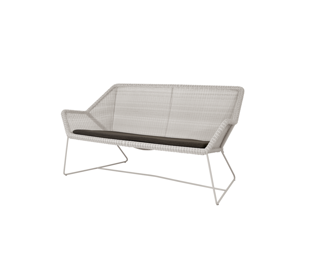 Moderne zand loveseat met een donkergrijze kussen.