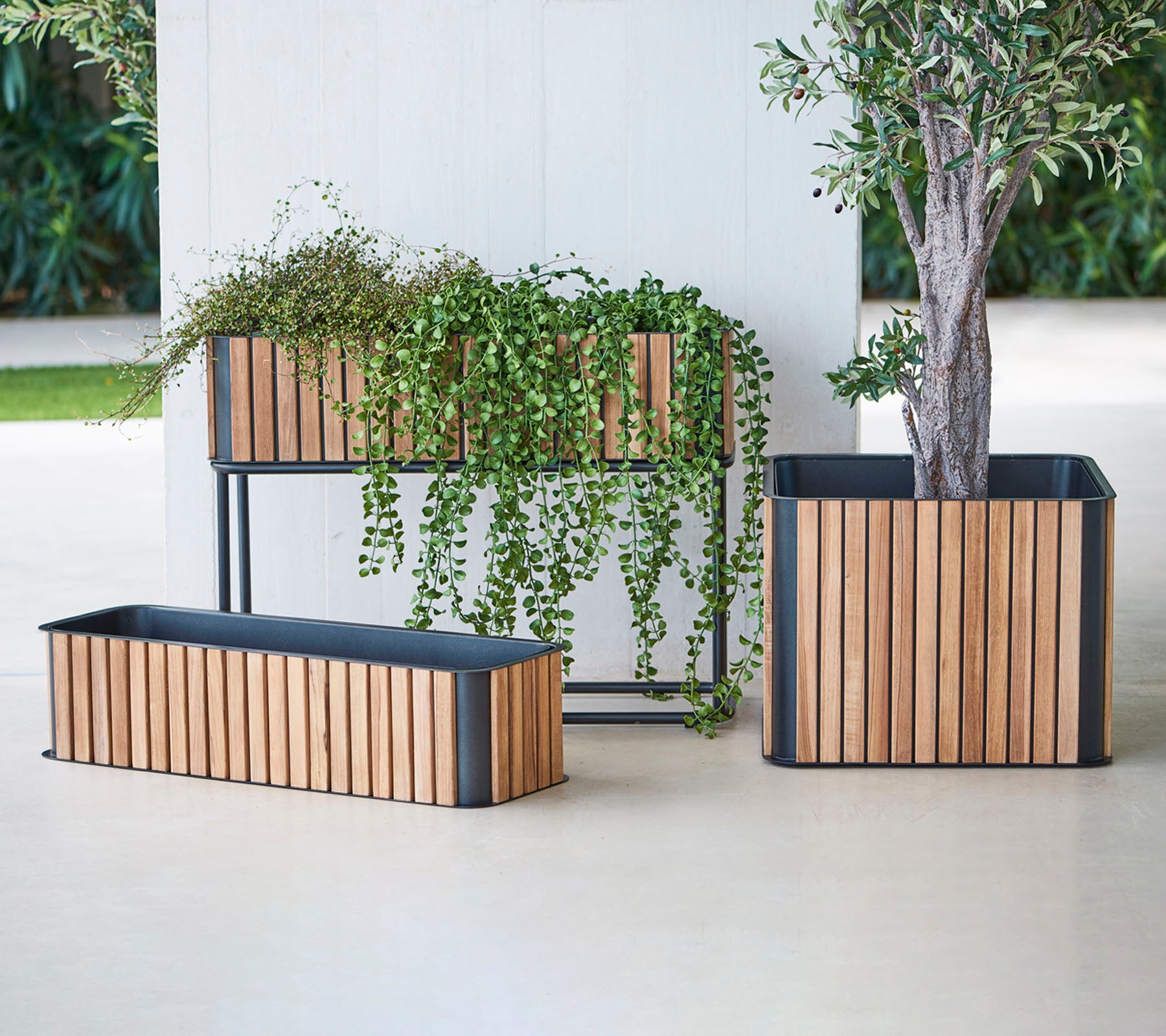 Drie stijlvolle plantenbakken met houten latten en metalen bases, die weelderig groen laten zien en een vleugje elegantie aan elke ruimte toevoegen.