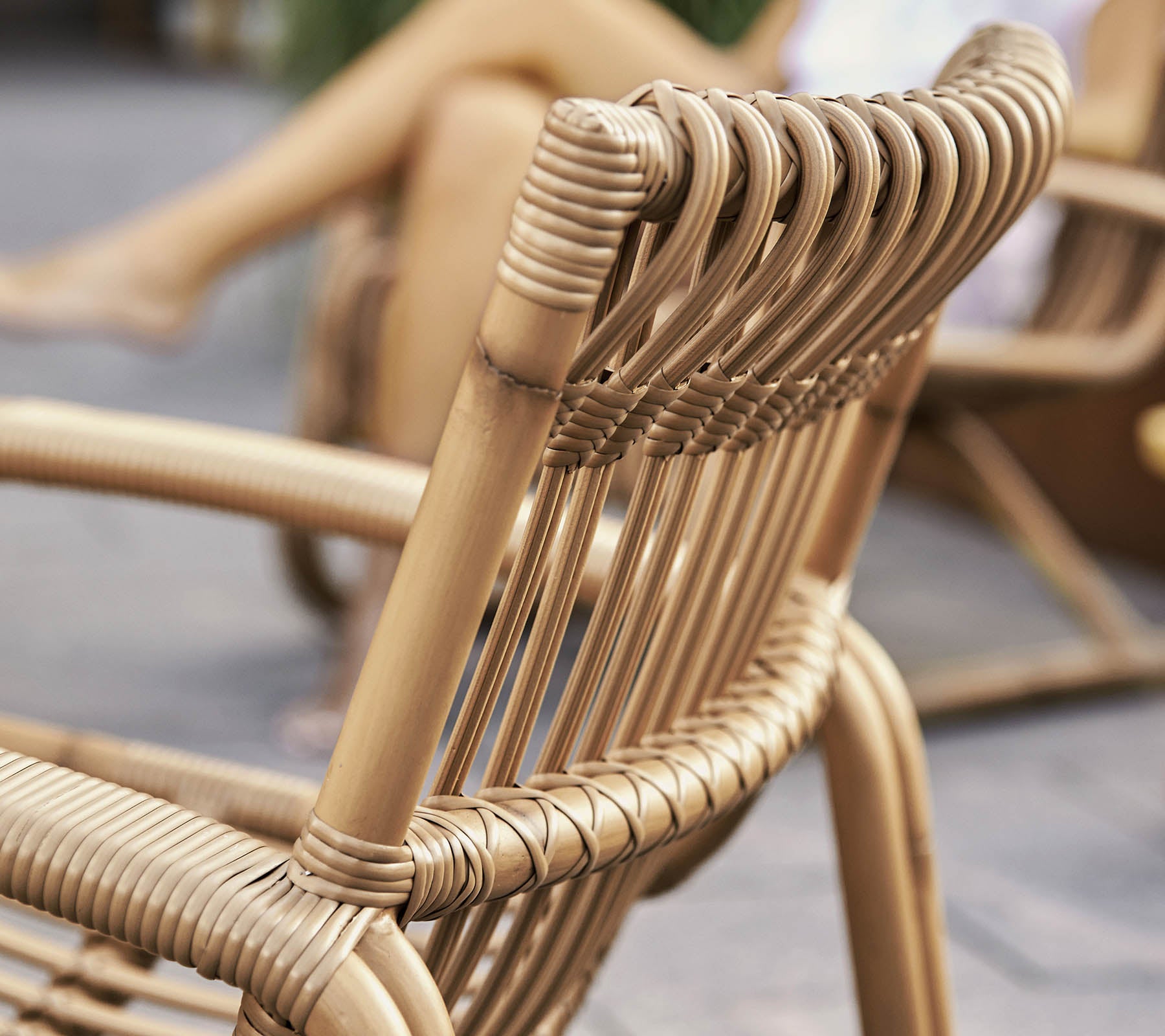 Close-up van een stijlvolle geweven stoel met een modern ontwerp, waarin gedetailleerd vakmanschap en natuurlijke materialen worden getoond.