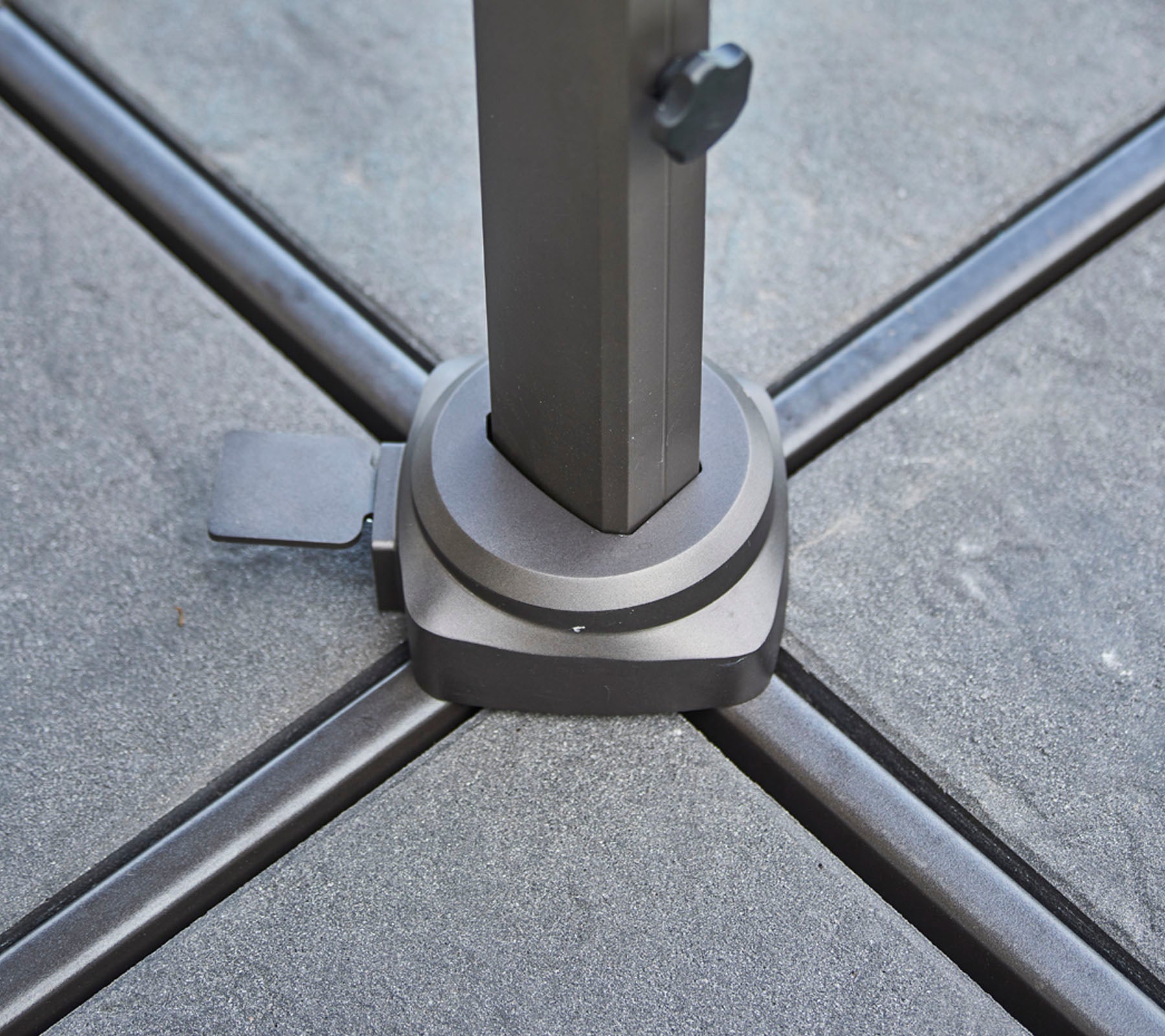 Basis van een steunpaal geplaatst op een gestructureerd oppervlak, met een klem voor stabiliteit en het veiligstellen van de paal op zijn plaats.