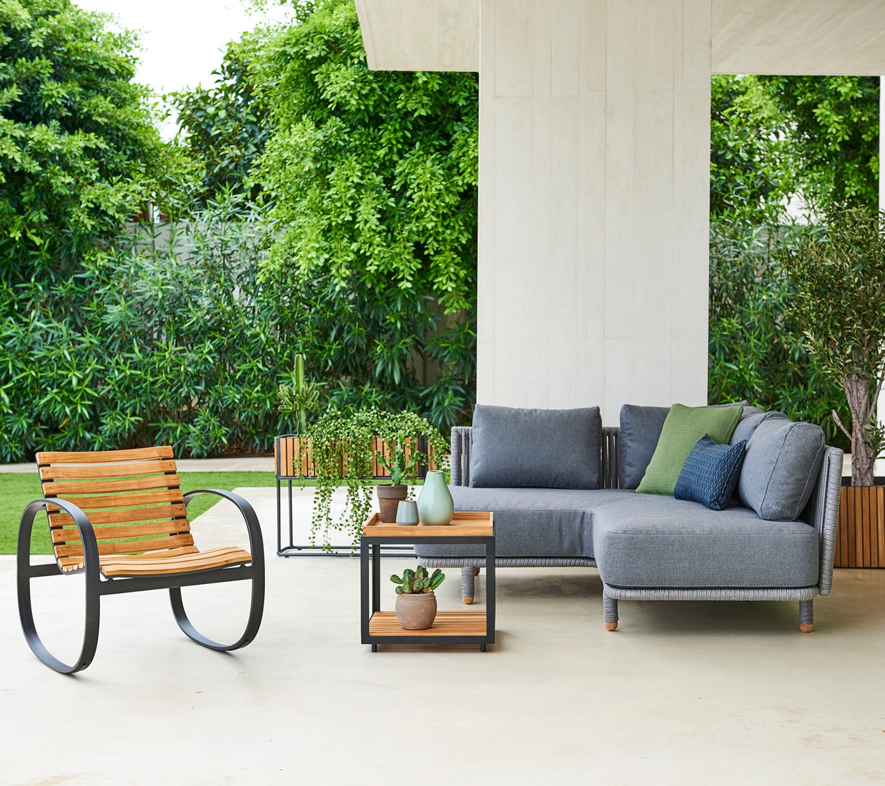 Hedendaagse zitopstelling met een modulaire sofa met kussens, een stijlvolle stoel en een bijzettafel met decoratieve planten.
