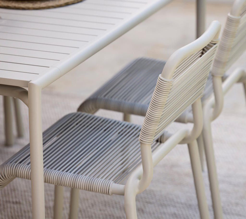 Moderne eettafel met witte afwerking en grijze stoelen.