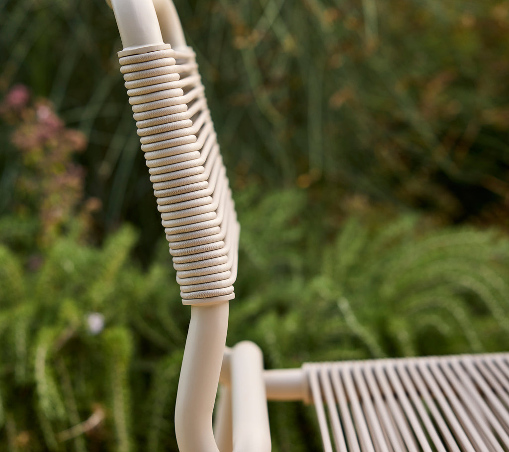 Beige stoel gedeeltelijk zichtbaar met een vage groene achtergrond.