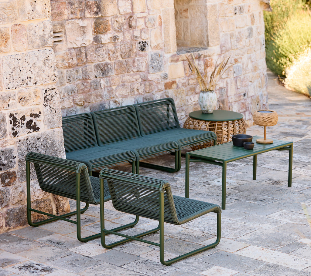Moderne groene bank en stoelen met een bijpassende tafel in een informele lounge-setting.