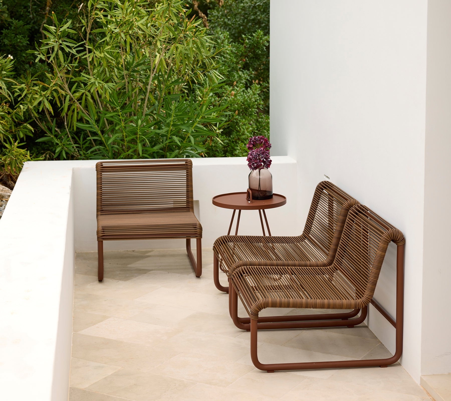 Moderne buitensalon met bruine stoelen en een ronde tafel.
