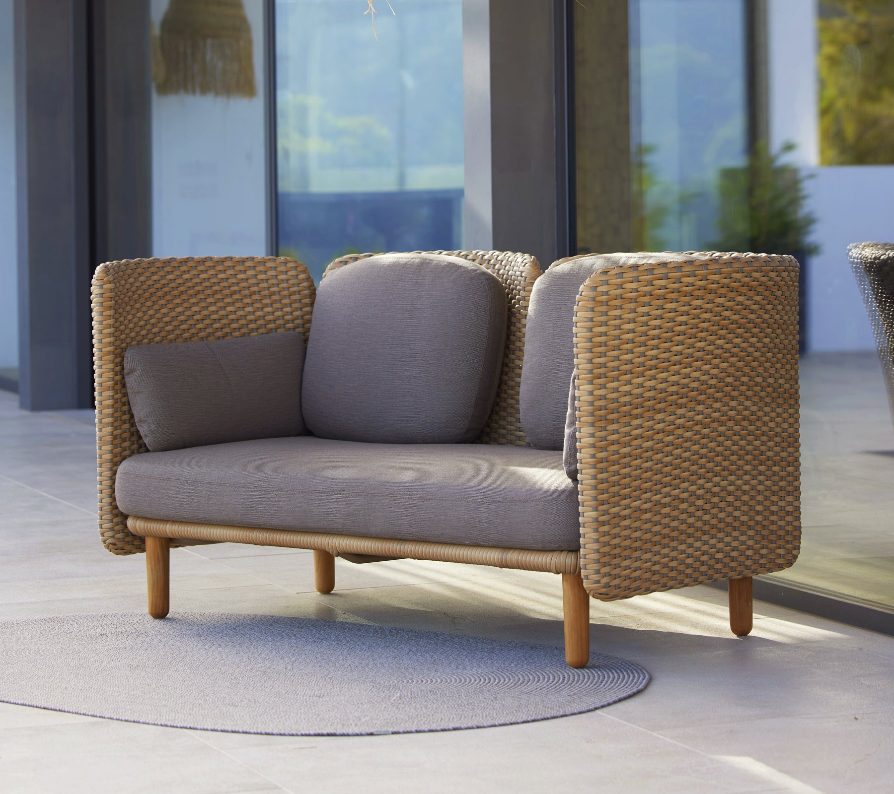 Arch 2-zitsbank met lage rugleuning, geweven zijkanten en neutrale kussens, die comfort met hedendaags design mengt.