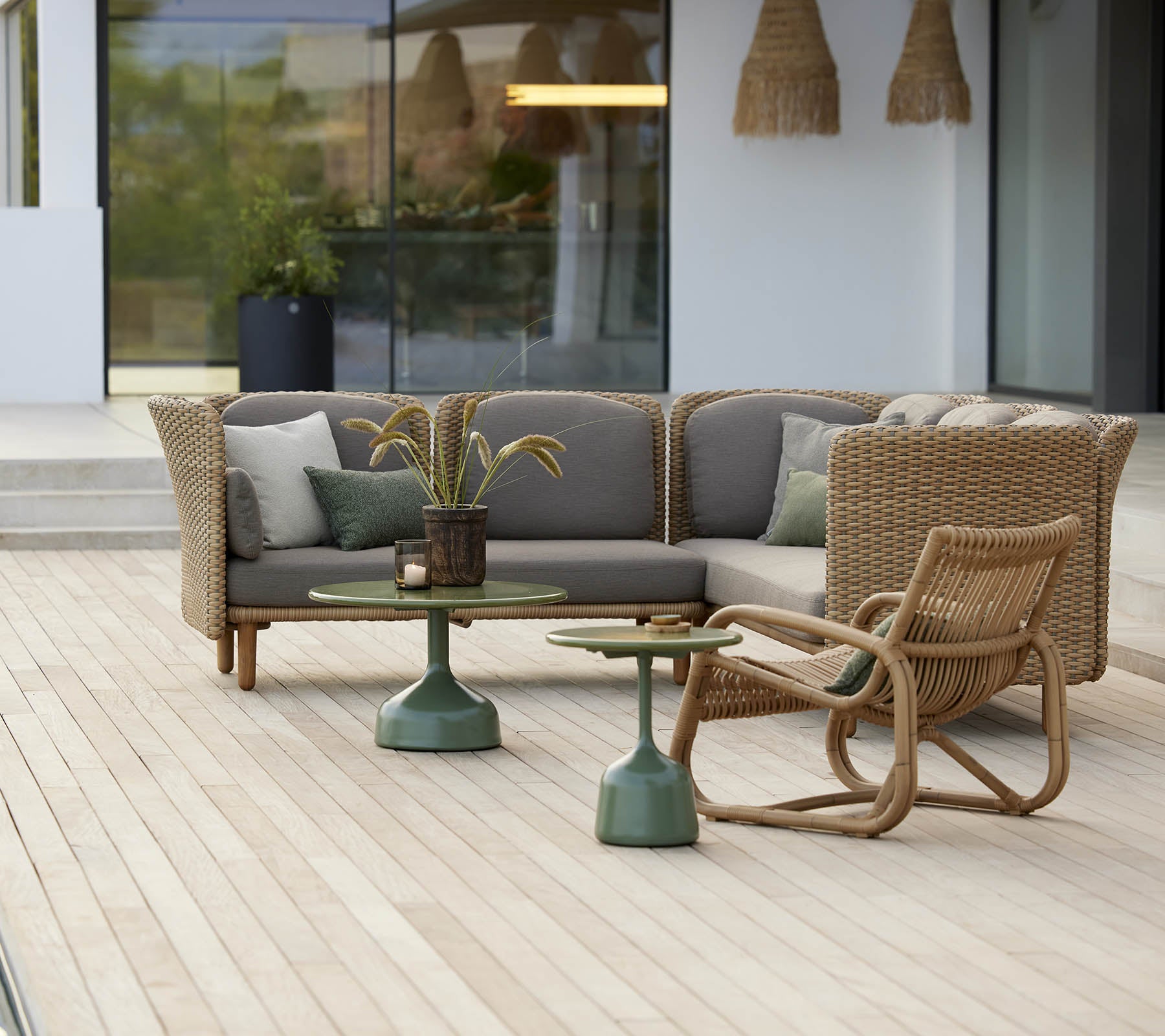 Stijlvol zitgedeelte met een gebogen loungestoel en een tafel met een groene basis, aangevuld met zachte kussens en decoratieve elementen.