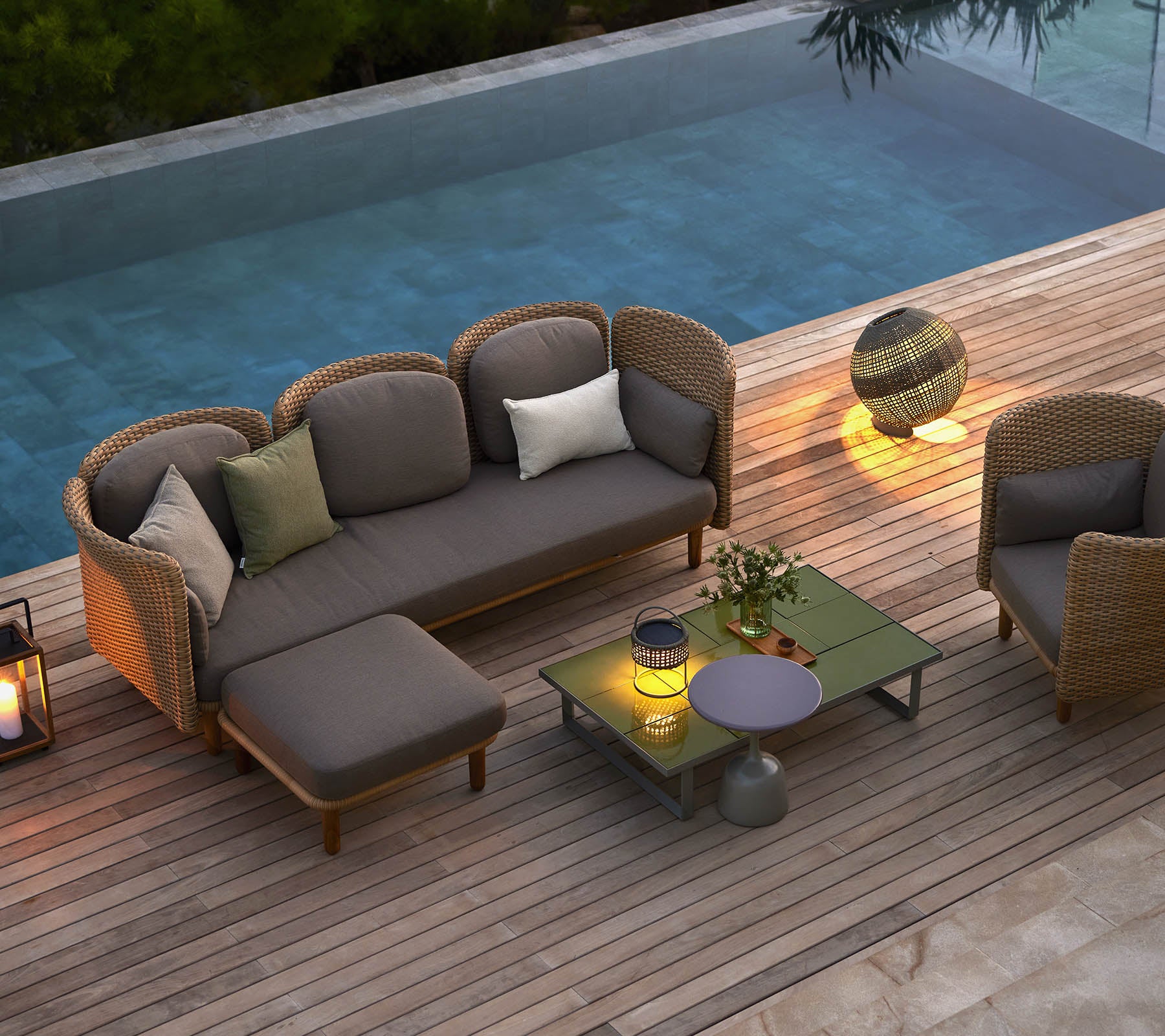 Stijlvolle loungezitplaatsen met kussens, een salontafel en sfeerverlichting, naast een serene pool.