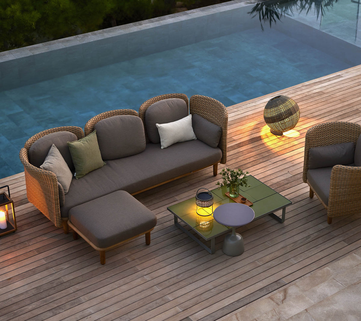 Stijlvolle loungezitplaatsen met kussens, een salontafel en sfeerverlichting, naast een serene pool.