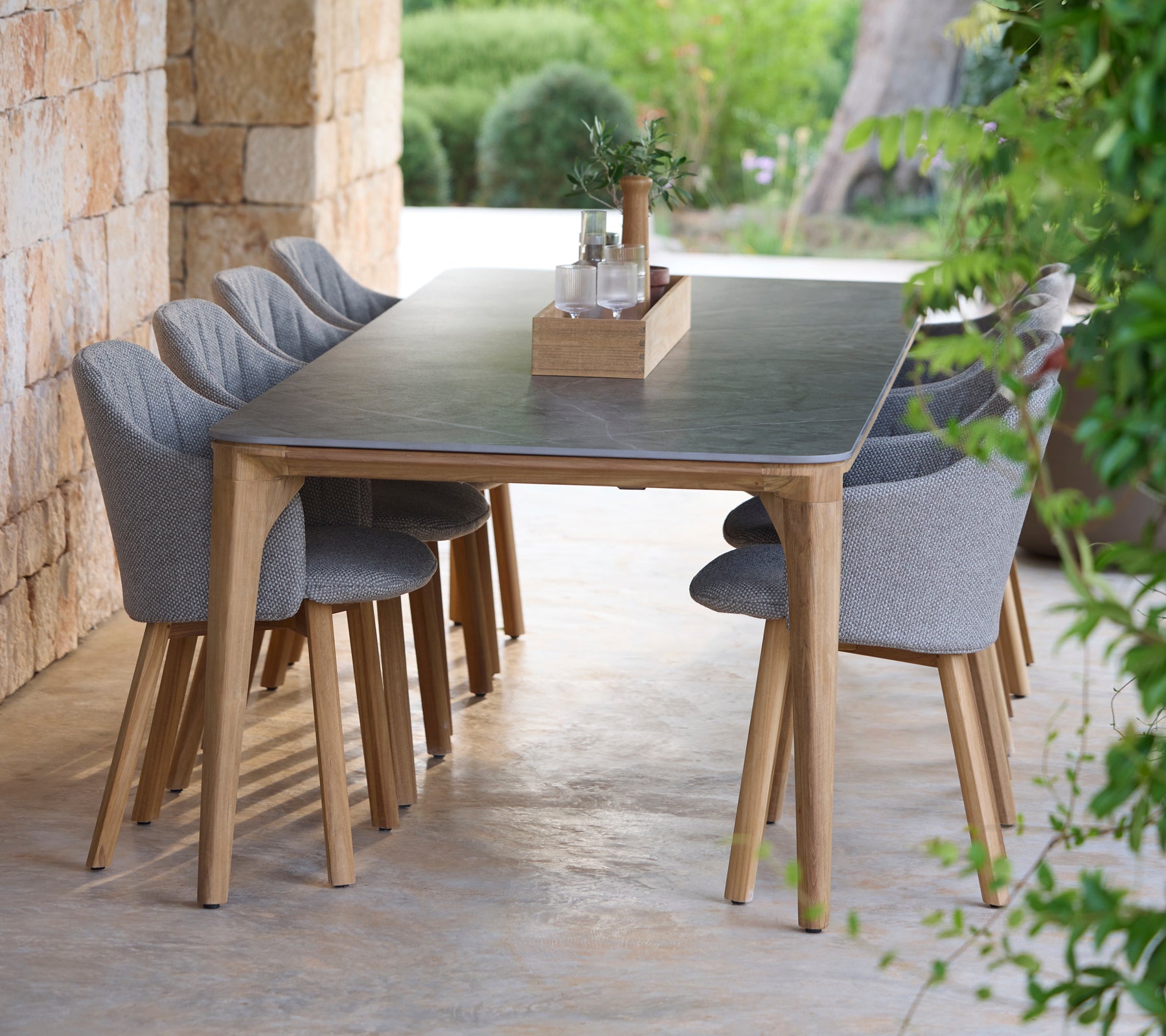 Modern eetset met grijze stoelen in een natuurlijke buitenomgeving.