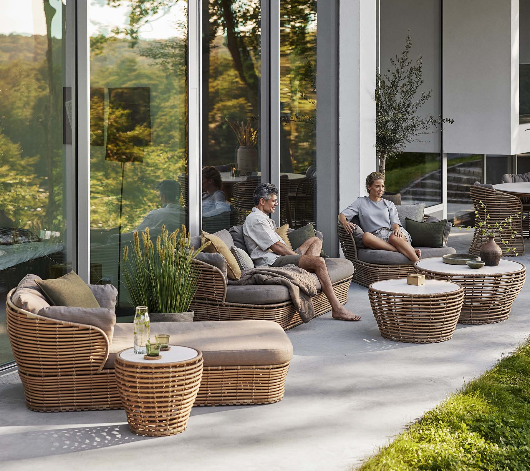 Stijlvol zitgedeelte met een mand zonnebed, loungestoel en salontafel met natuurlijke elementen, die een gezellige, ontspannen sfeer creëren.
