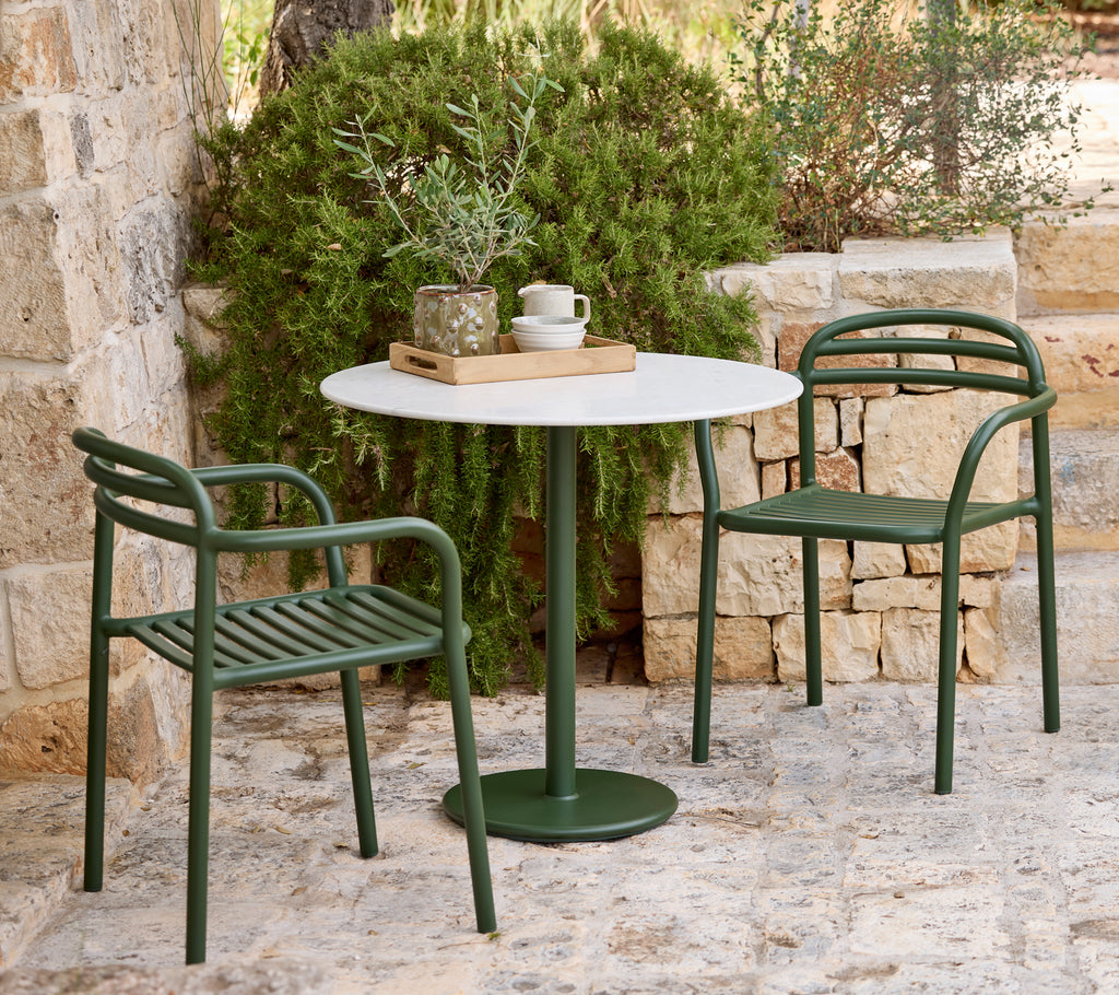 Moderne buitensetting met groene stoelen en een witte tafel.