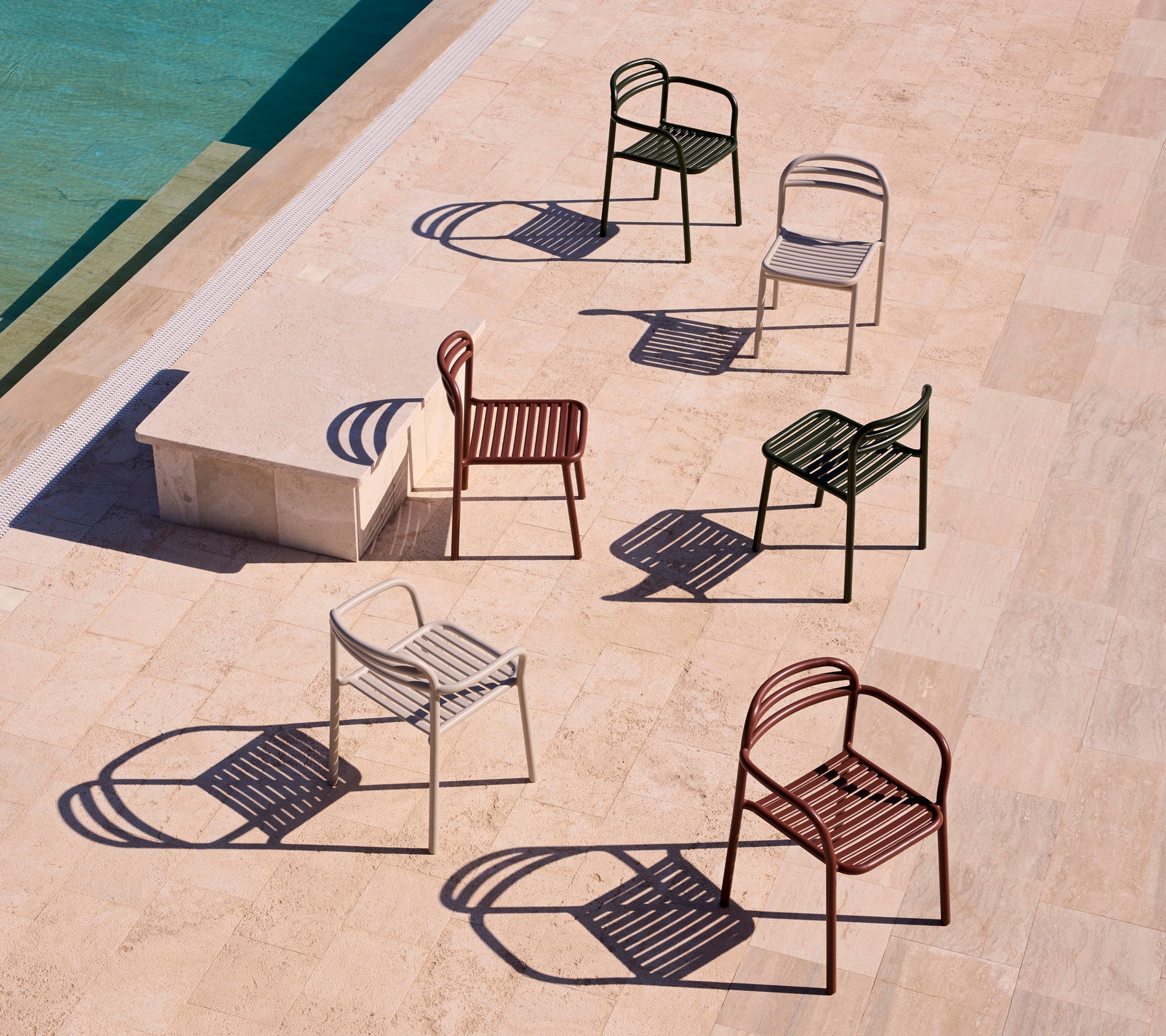 Een collectie Bliss-stoelen met armleuningen in verschillende kleuren, die schaduwen werpen op een lichte ondergrond.