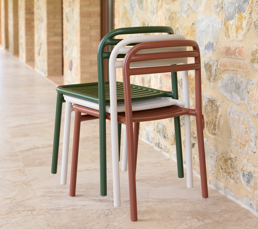 Een stapel Bliss-stoelen in verschillende kleuren, die een slank ontwerp en praktische ruimtebesparende opslag toont.