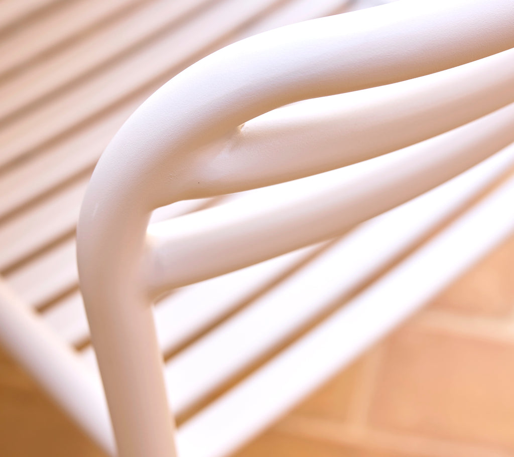 Close-up van een zandkleurige eetkamerstoel die soepele, gebogen lijnen en een strak ontwerp laat zien, dat moderne stijl en comfort benadrukt.